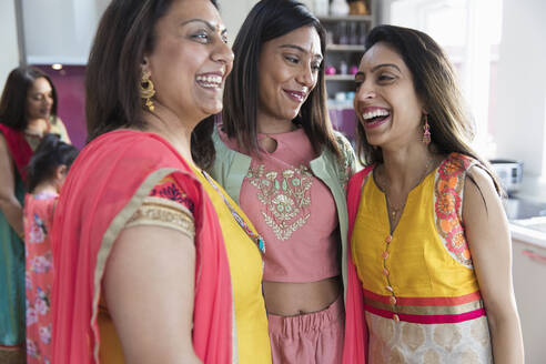 Happy Indian sisters in saris laughing in kitchen - CAIF29020