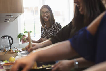 Happy Indian women cooking food in kitchen - CAIF29023