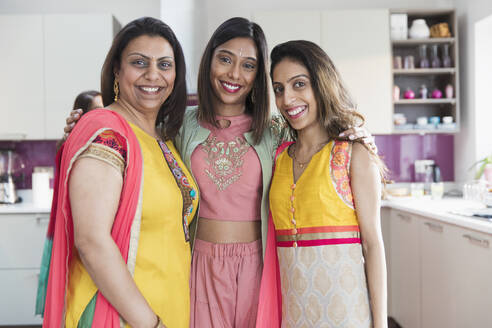 Portrait happy Indian sisters in saris in kitchen - CAIF29040