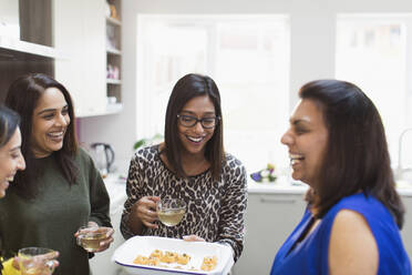 Glückliche indische Frauen mit Tee und Essen in der Küche - CAIF29052