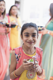 Portrait smiling Indian girl in sari and bind with bowl of rice - CAIF29056