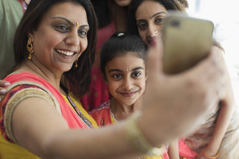 Happy Indian women in bindis and saris taking selfie with camera phone - CAIF29074