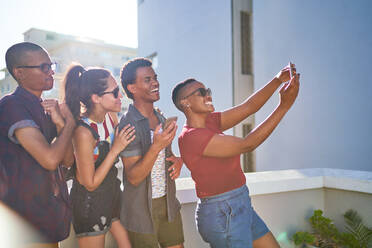 Glückliche junge Freunde nehmen Selfie auf sonnigen städtischen Balkon - CAIF29081
