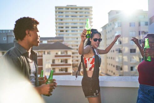 Unbekümmerte junge Freunde tanzen auf einem sonnigen städtischen Dachbalkon - CAIF29089
