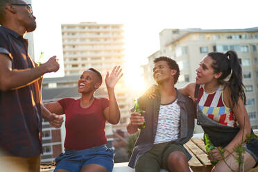 Glückliche junge Freunde trinken Bier auf einem sonnigen Dach in der Stadt - CAIF29091