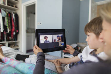Family video chatting with digital tablet on bed - CAIF29099