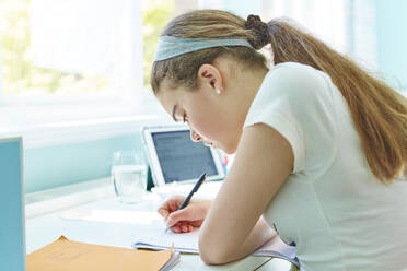 Focused girl doing homework at desk - CAIF29113