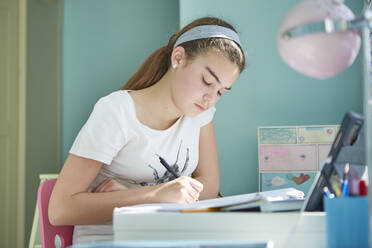 Girl doing homework at desk in bedroom - CAIF29119