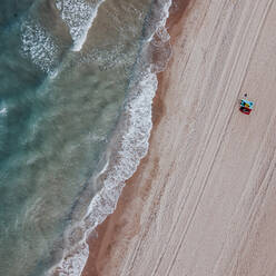 Von oben Drohne Blick auf unerkennbare Paar liegen zusammen auf Sandstrand in der Nähe von herrlichen stürmischen Meer - ADSF06572