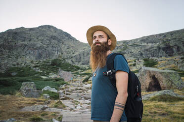 Young man standing at bottom of mountain - ADSF06577