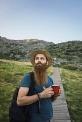 Young man standing in field with cup - ADSF06579