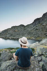 Young man sitting on rocks near lake - ADSF06583