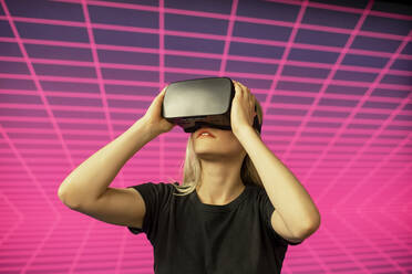 Female scientist looking through virtual reality simulator against grid pattern - BFRF02281