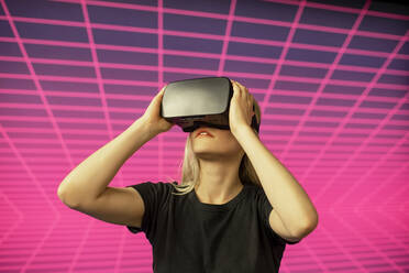 Wissenschaftlerin schaut durch einen Virtual-Reality-Simulator auf ein Gittermuster - BFRF02281