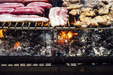 Close-up of meat and coals on barbecue grill in yard - JCMF01058