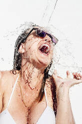 Nahaufnahme von Wasser, das auf den Kopf einer fröhlichen Frau an der Wand spritzt - JCMF01089