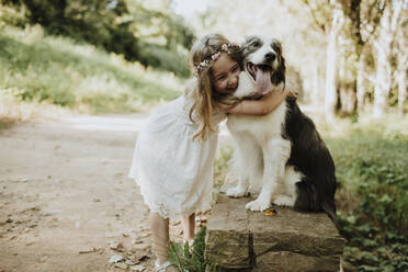 Mädchen umarmt Border Collie in der Natur - GMLF00338