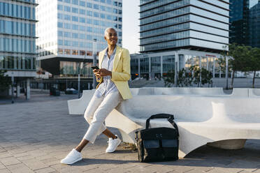 Businesswoman looking away while using smart phone in city - JRFF04644