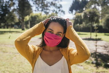 Nahaufnahme einer jungen Frau mit Maske, die an einem sonnigen Tag im Park steht - DSIF00062