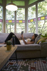 Frau liest Buch auf Sofa zu Hause - VEGF02549