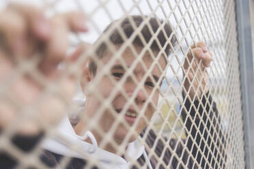 Portrait of a young teenage boy leaning on a fence in the city - ADSF06720