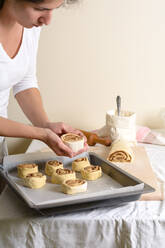 Crop hands putting buns of baking pan - ADSF06727