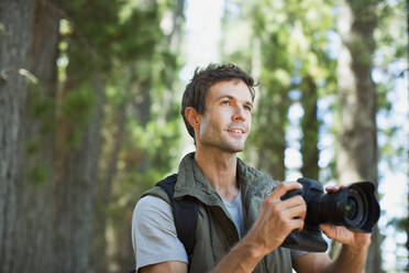 Mann mit Digitalkamera im Wald - CAIF29122