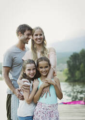 Smiling family on dock over lake - CAIF29123