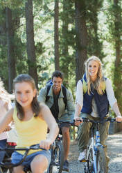 Lächelnde Familie beim Radfahren im Wald - CAIF29127