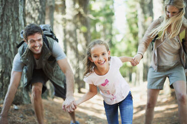 Familie hält sich an den Händen und läuft im Wald - CAIF29134