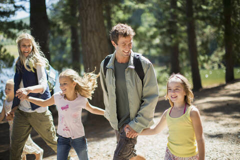 Smiling family holding hands and walking in woods stock photo