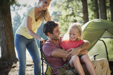 Smiling family at campsite in woods - CAIF29146
