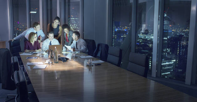 Business people working at laptop in conference room at night - CAIF29224