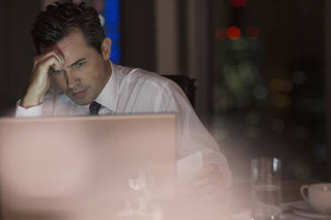 Stressed businessman working late at laptop in office - CAIF29265