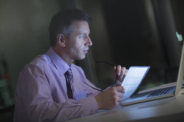 Businessman working late at laptop in office - CAIF29313