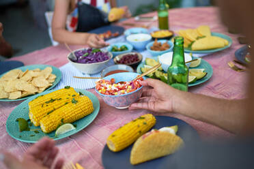 Friends eating tacos and corn at patio table - CAIF29332