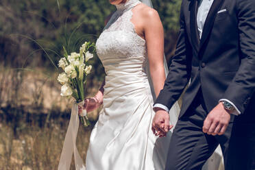 Verheiratetes Paar in Hochzeitskleidung hält Hände - ADSF06907