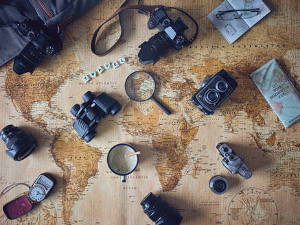 Becher mit frischem Kaffee und diversem Touristenkram auf einer Retro-Weltkarte liegend - ADSF06949