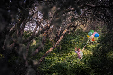 Little boy walking on meadow with balloons - ADSF06960