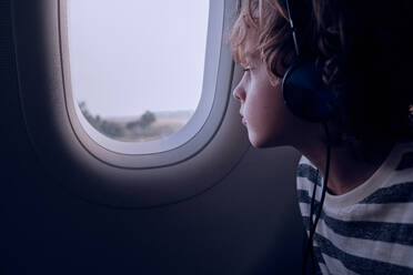 Niedlicher Junge mit Kopfhörern im Flugzeug - ADSF06975