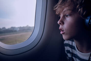 Cute boy with headphones in plane - ADSF06990