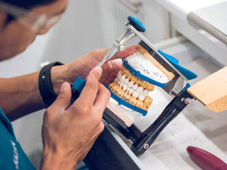 Dental technician holding artificial teeth on holder - ADSF07065