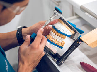 Zahntechniker hält künstliche Zähne auf einem Halter - ADSF07065