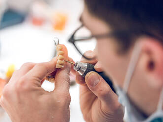 Crop man applying substance on denture - ADSF07069