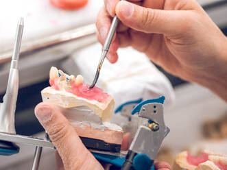 Crop man applying substance on denture - ADSF07070