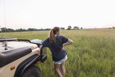 Dreizehnjähriges Mädchen lehnt an einem Safarifahrzeug, Botswana - MINF14744