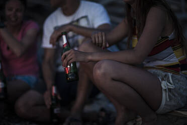Eine Gruppe junger Leute hat sich an einem Strand versammelt und trinkt Bier. - MINF14846