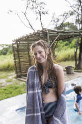Lächelndes dreizehnjähriges Mädchen an einem Swimmingpool in einem Safari-Resort. - MINF14915