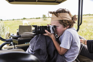 Six year old boy taking pictures from safari vehicle, Botswana - MINF14935