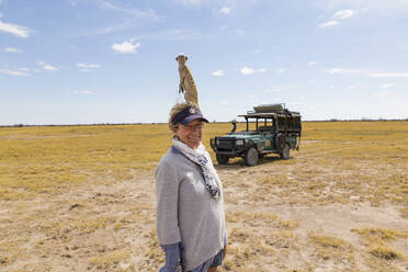 Erwachsene Frau mit Erdmännchen auf dem Kopf, Kalahari-Wüste, Makgadikgadi-Salzpfannen, Botswana - MINF14969